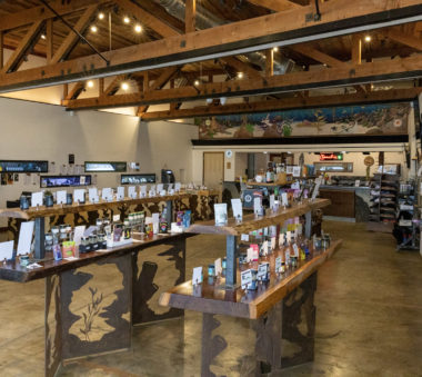 Interior of a well-lit store with wooden beams and tables displaying various packaged products