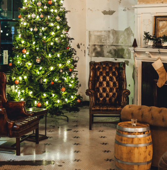 Cozy lounge with leather chairs, a decorated Christmas tree, and a festive fireplace