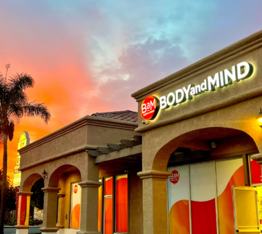 BaM Body and Mind storefront glowing at sunset with palm trees and vibrant sky in the background.